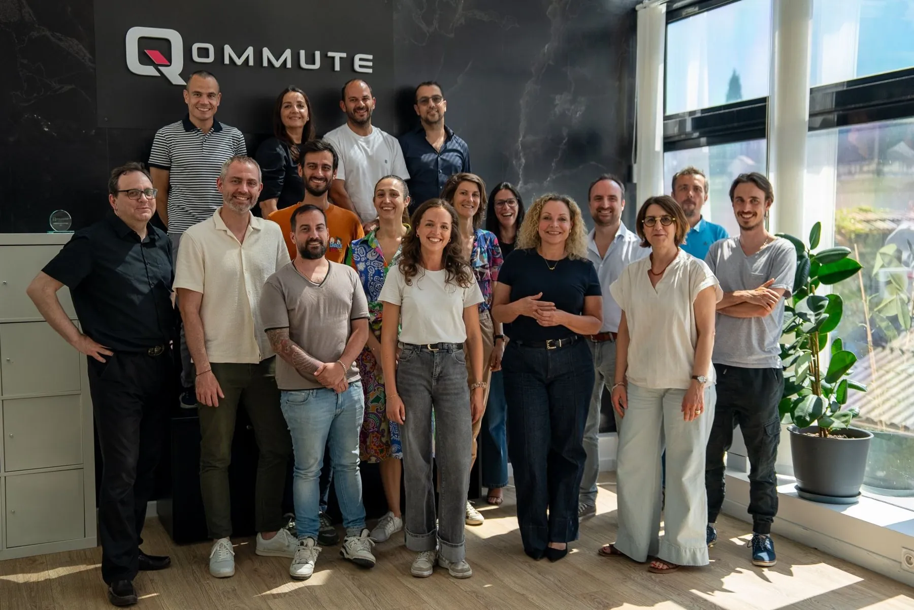 Das Qommute-Team in seinen Büros in Marseille, vor dem Qommute-Logo.